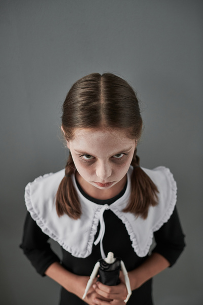 Girl in Halloween Costume Holds Doll without Head